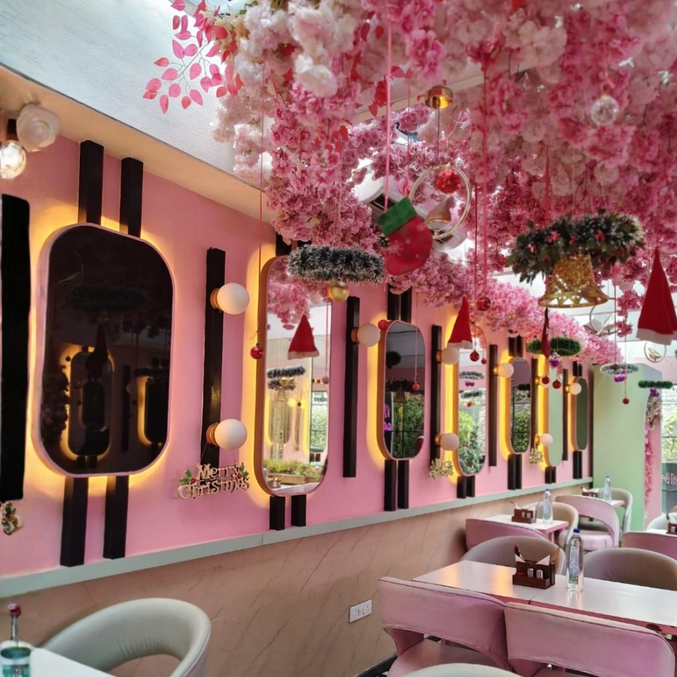 The image shows a floral themed cafe with mirrors on the wall. There are chairs and table and the place looks very fancy.